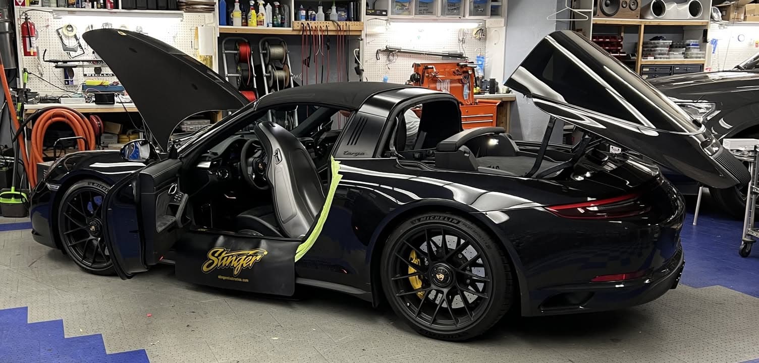 Black Porsche Targa 4 GTS in the Car Audio Innovations shop with its driver door and storage lids open