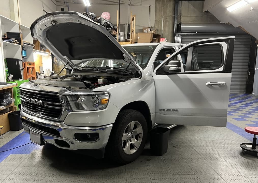 White Ram pickup in the Car Audio Innovations shop with its hood and front doors open